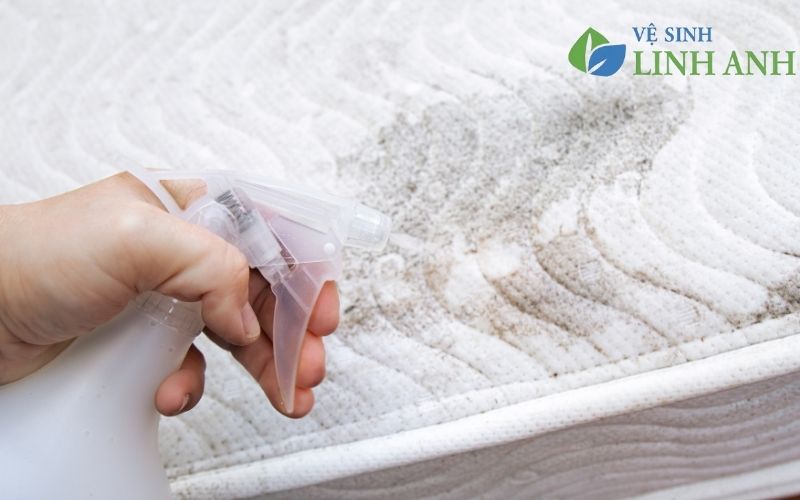 Nhân viên đang sử dụng hóa chất để xử lý vết bẩn cứng đầu trên nệm